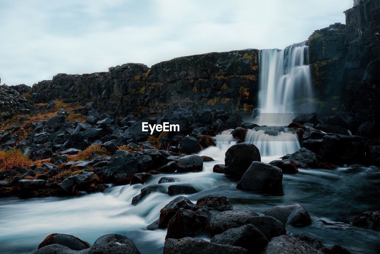 Scenic view of waterfall against rocky mountains
