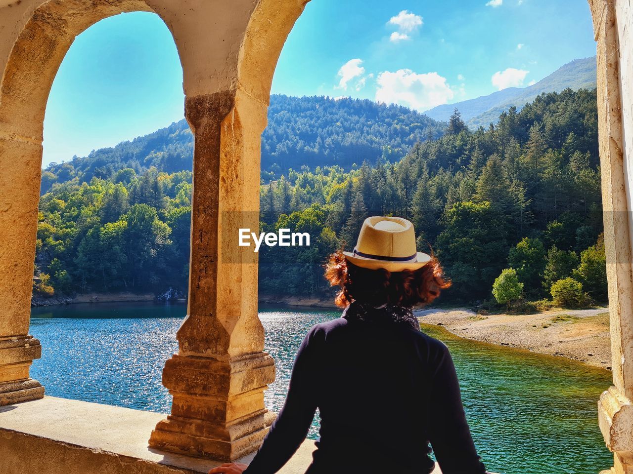 Woman from behind with hat looks at the wonderful lake of san domenico in abruzzo