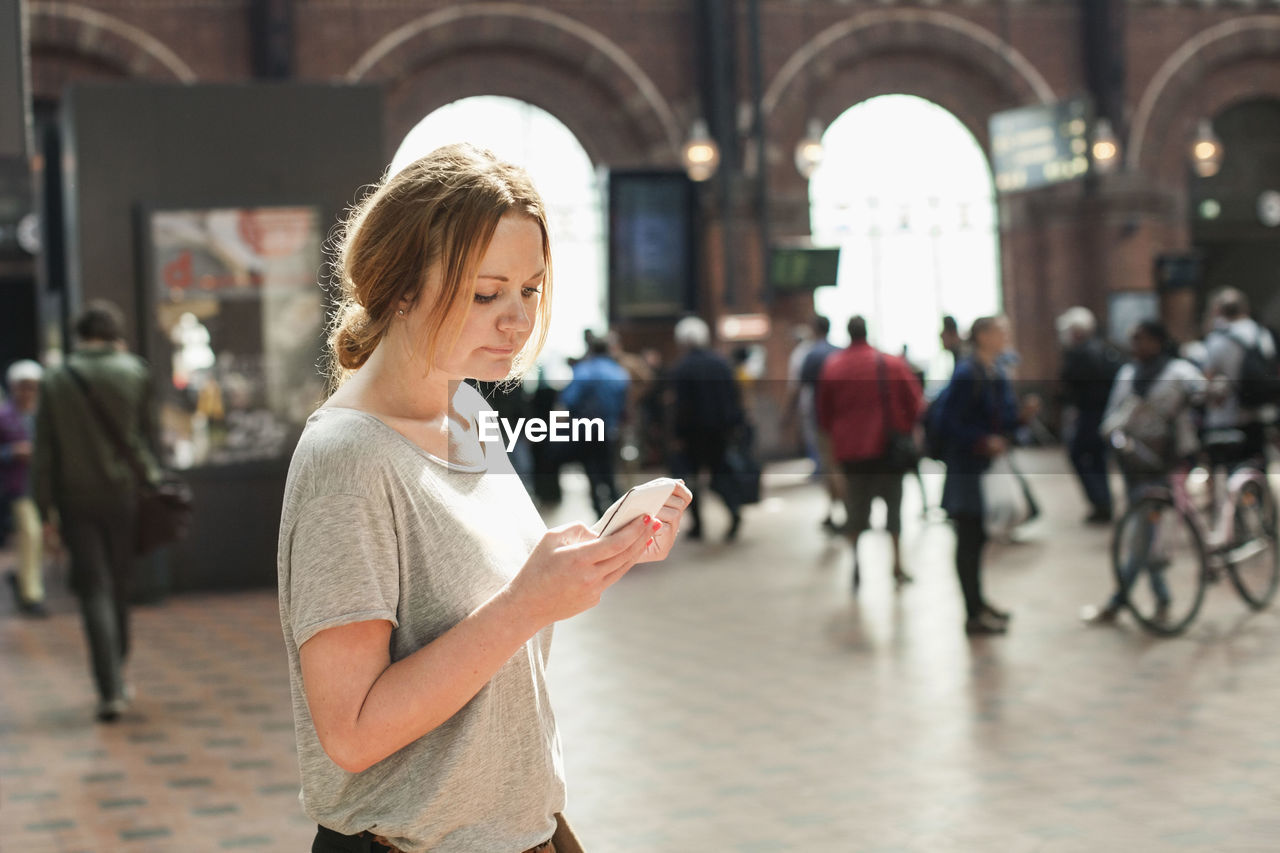 Mid adult woman using mobile phone on railway station