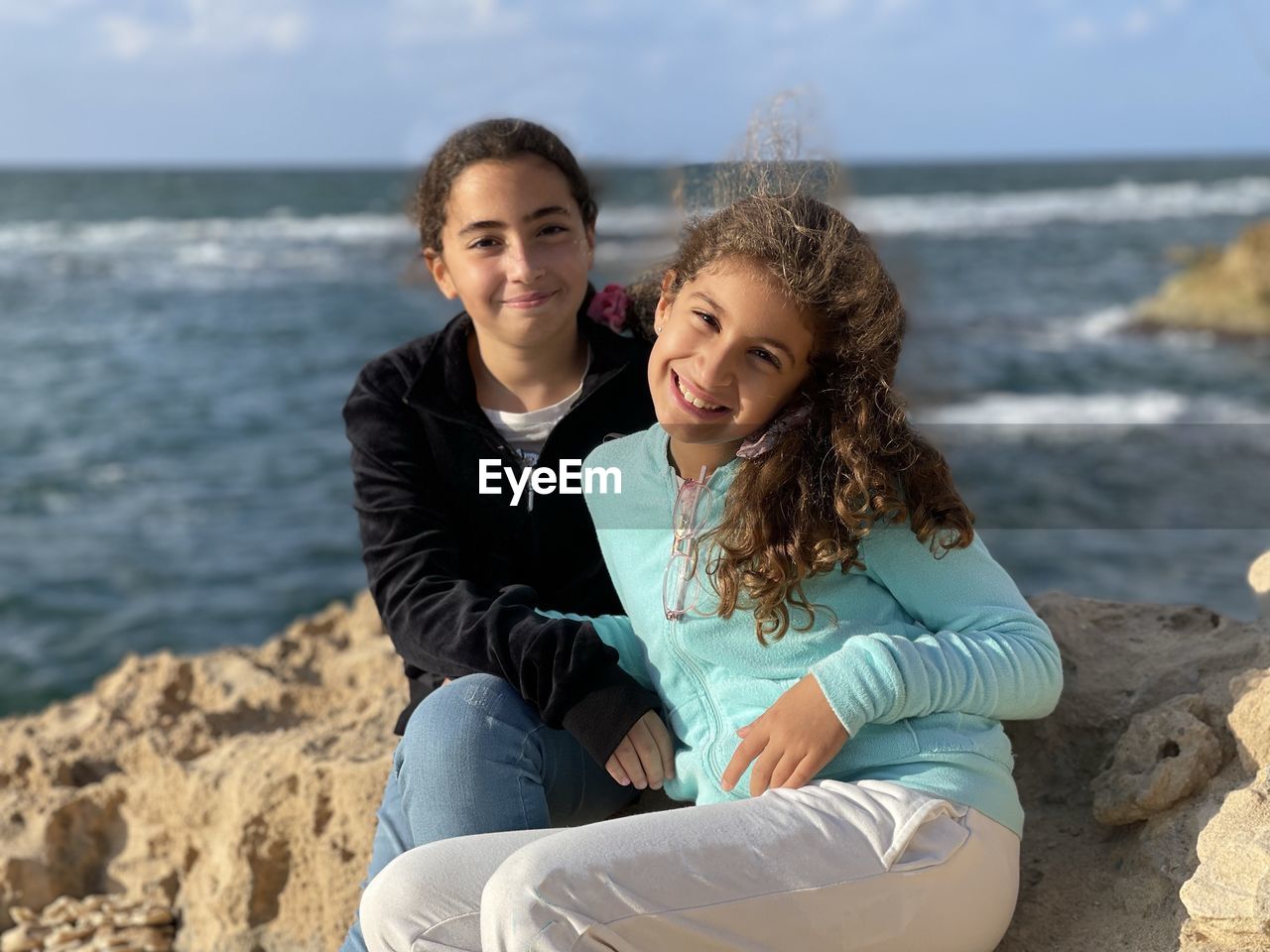 Portrait of two young girls sitting at beach