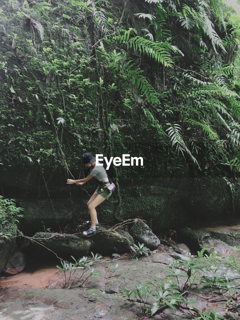 Full length of woman standing on rock in forest