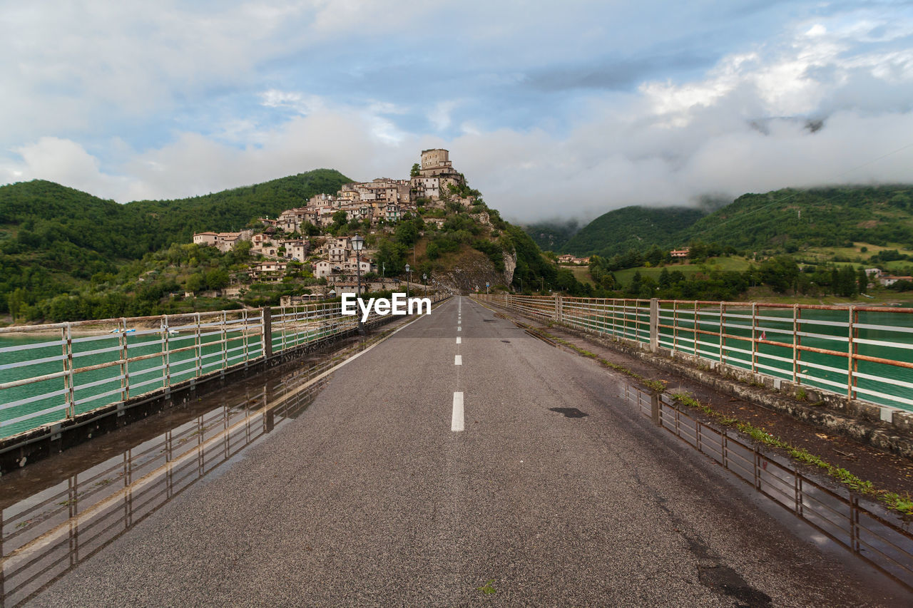 Road leading towards mountains against sky