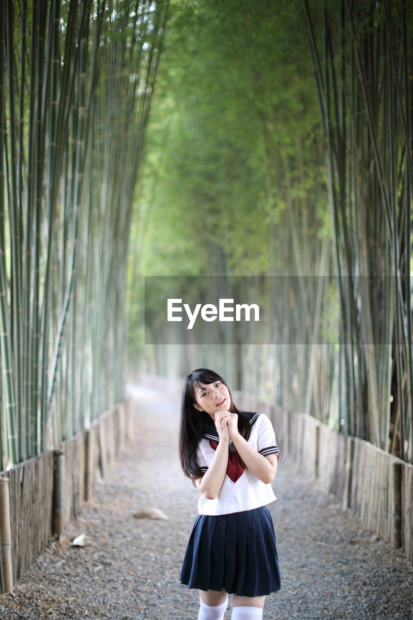 Portrait of young woman while standing amidst bamboo groove