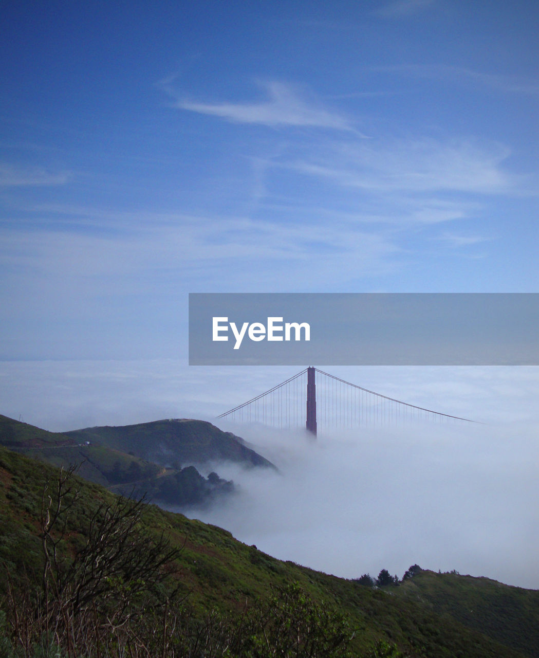 Scenic view of mountain and golden gate bridge with clouds against sky