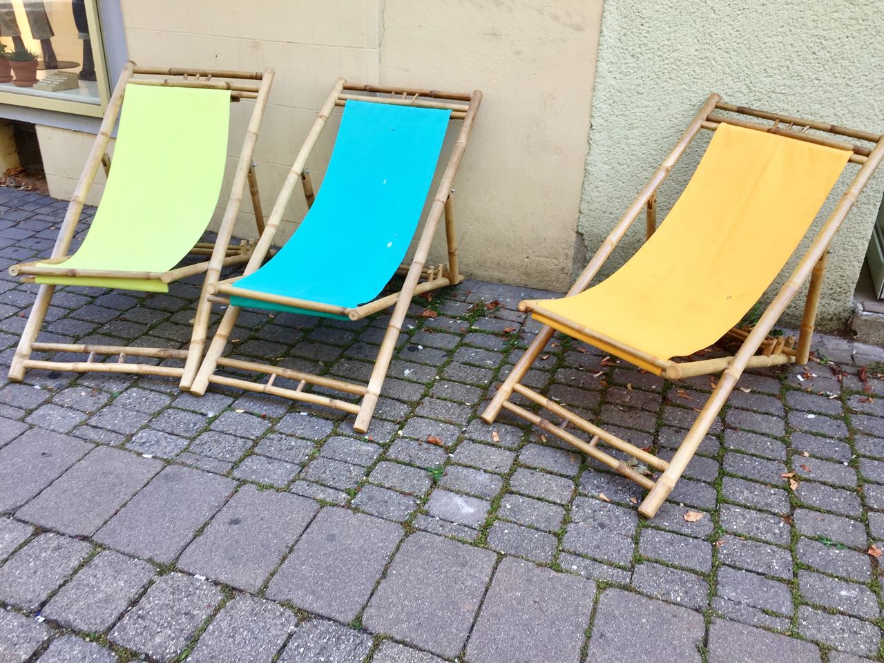 EMPTY CHAIRS AND TABLES ON SIDEWALK AGAINST WALL