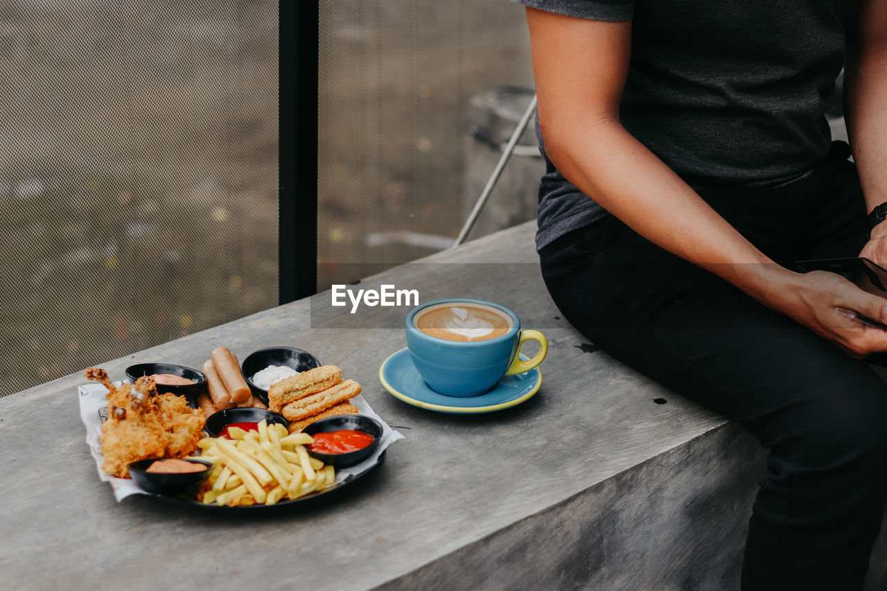 Midsection of man sitting on table at restaurant