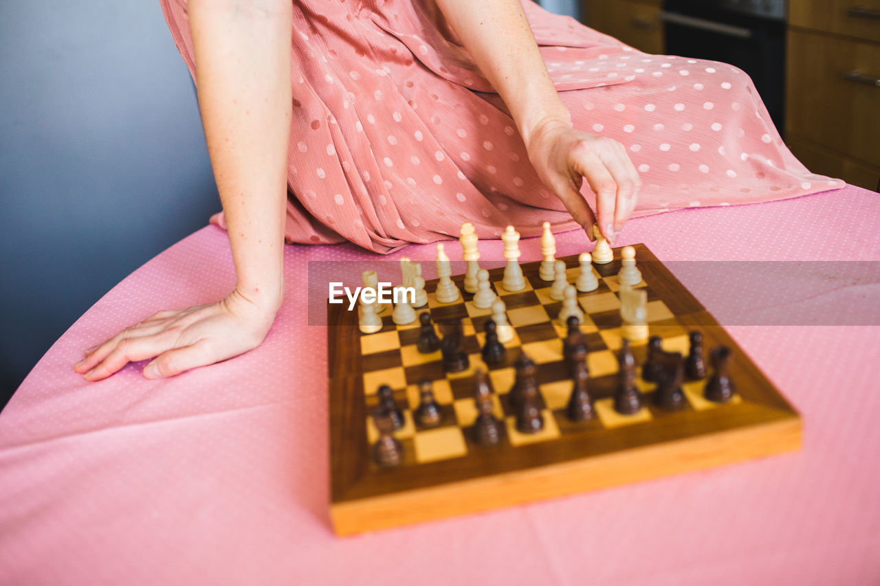 Midsection of woman dressed in pink playing chess 