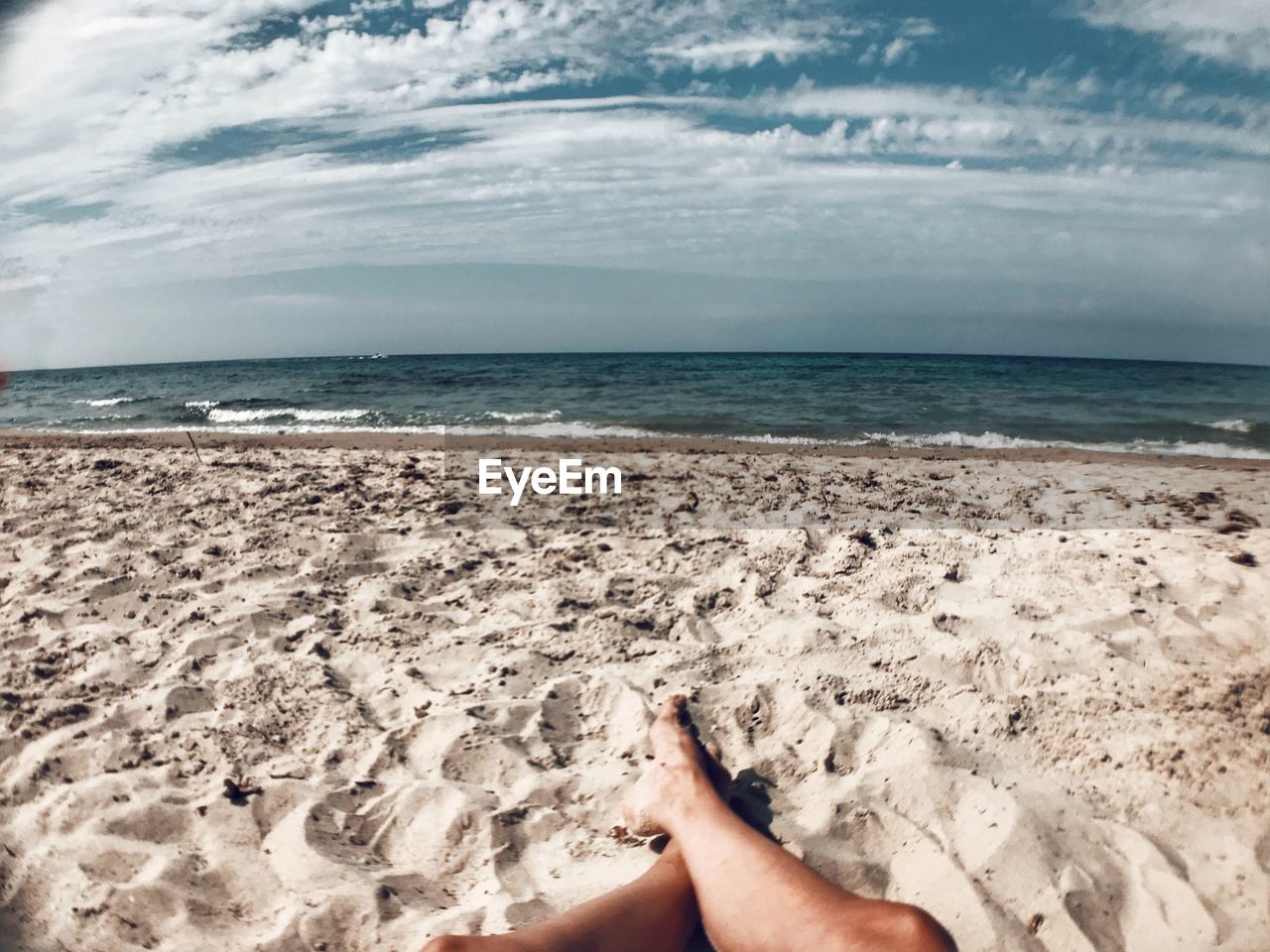 Low section of man relaxing on at sandy beach