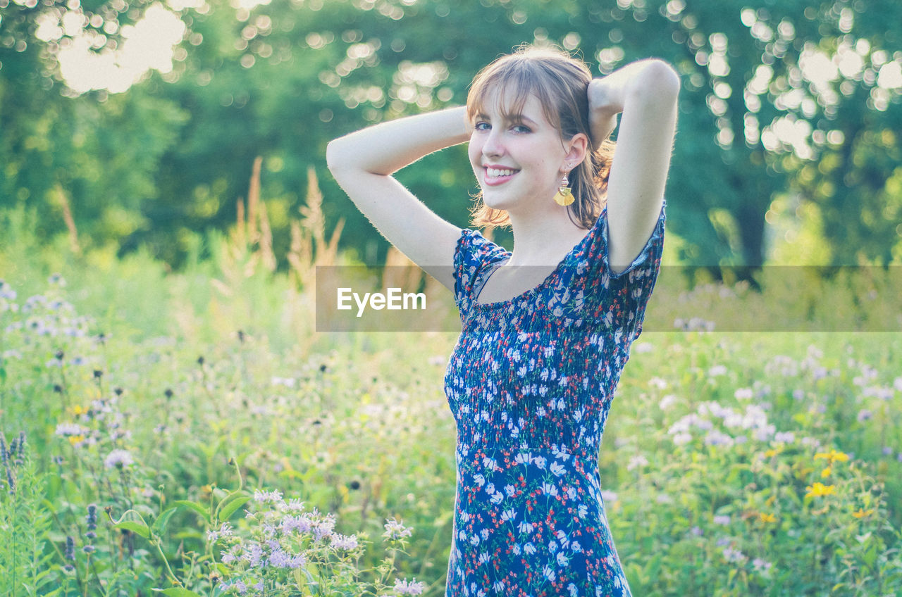 Portrait of smiling young woman standing at field