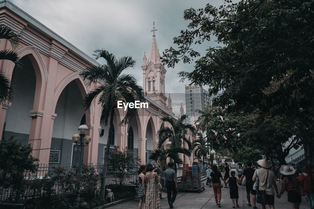 PEOPLE ON STREET AMIDST BUILDINGS AGAINST SKY