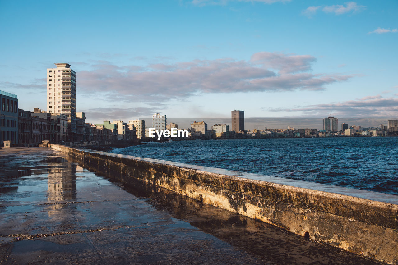 Sea by buildings against sky in city