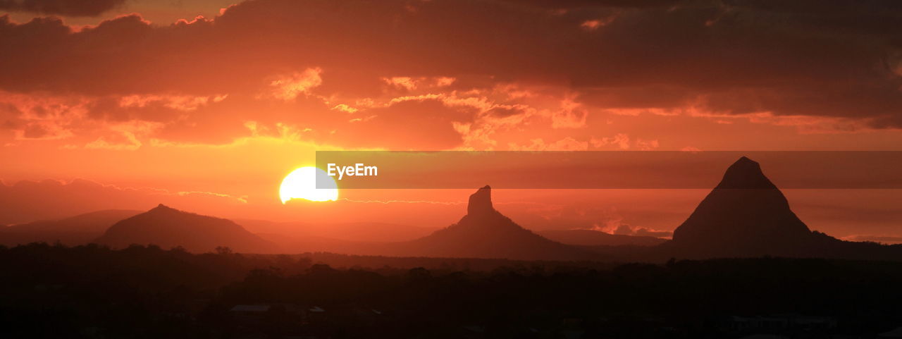 Scenic view of silhouette mountains against orange sky