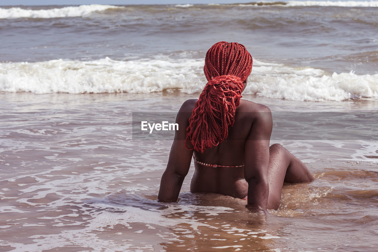 African woman sitting on the sea shore with red hair in ghana west africa