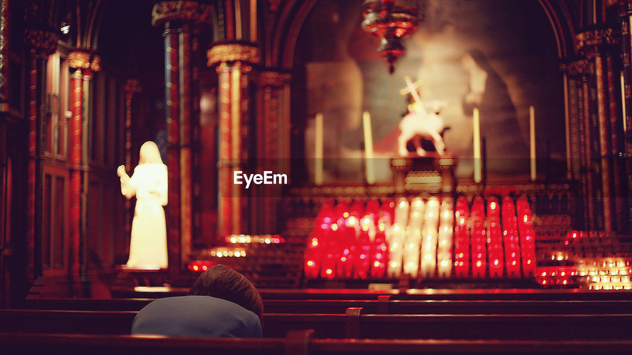 Rear view of person praying in church