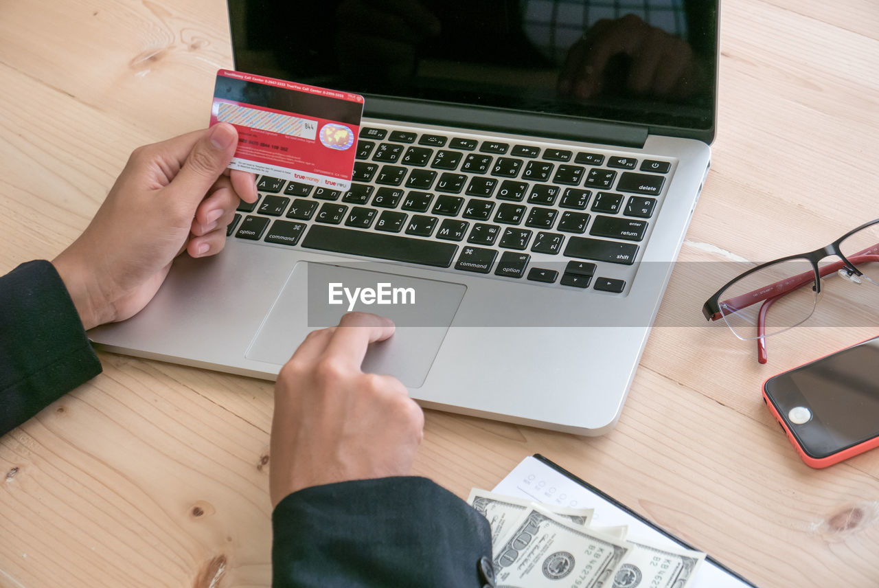 Cropped image of businesswoman holding credit card at desk in office