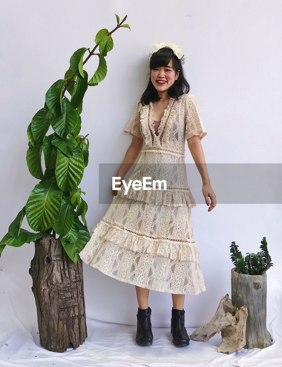 Portrait of young asian woman standing against plants over white background 