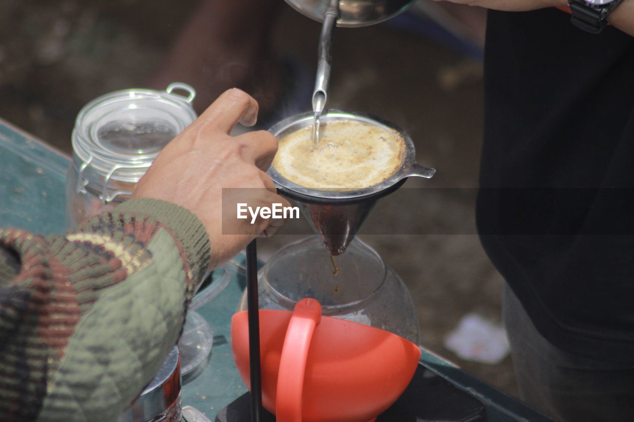 Close-up of hand pouring coffee in glass