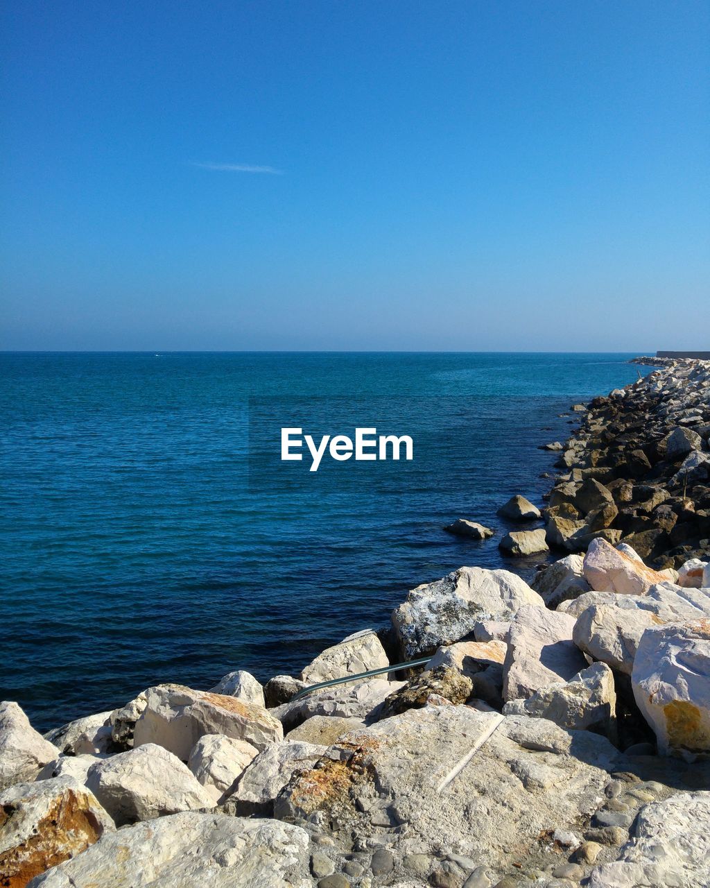 ROCKS IN SEA AGAINST CLEAR BLUE SKY