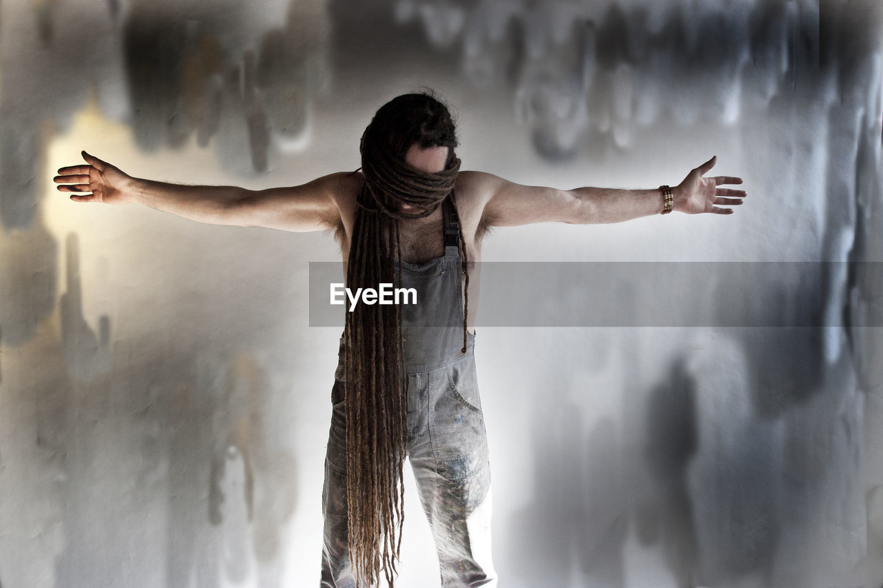 Man with dreadlocks standing against abandoned wall