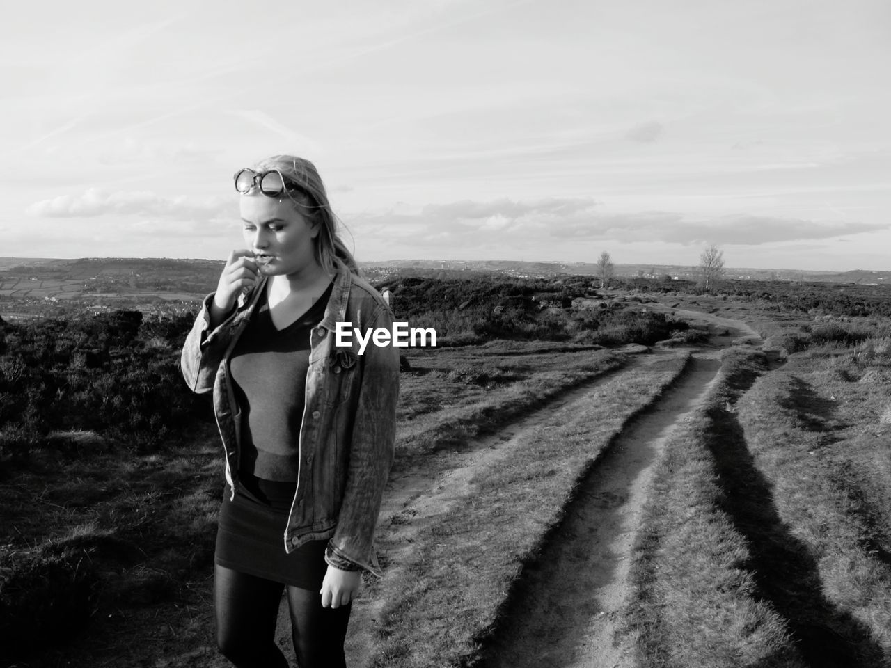 Thoughtful woman standing on field against sky