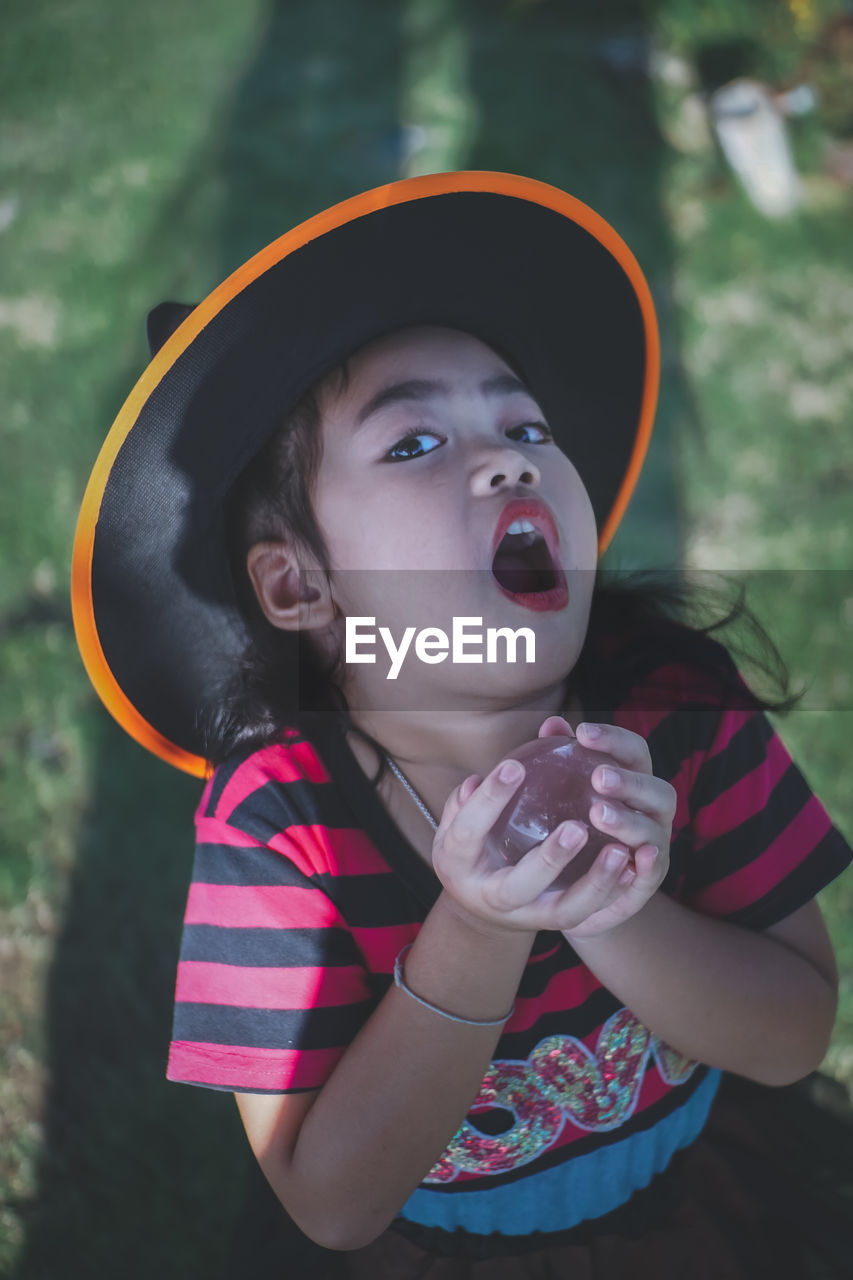 Portrait of girl wearing witch hat holding crystal ball