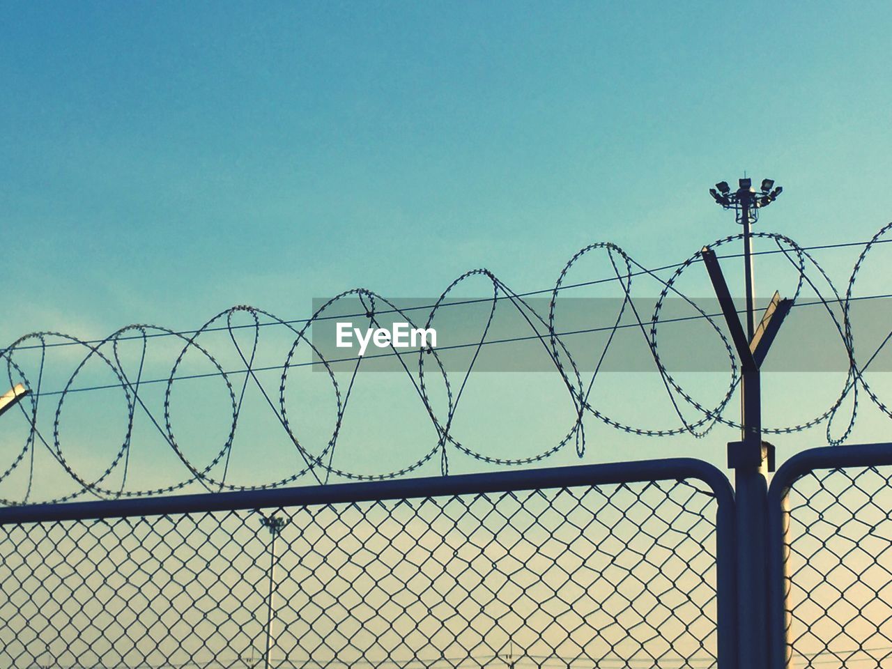 METAL CHAINLINK FENCE AGAINST CLEAR SKY