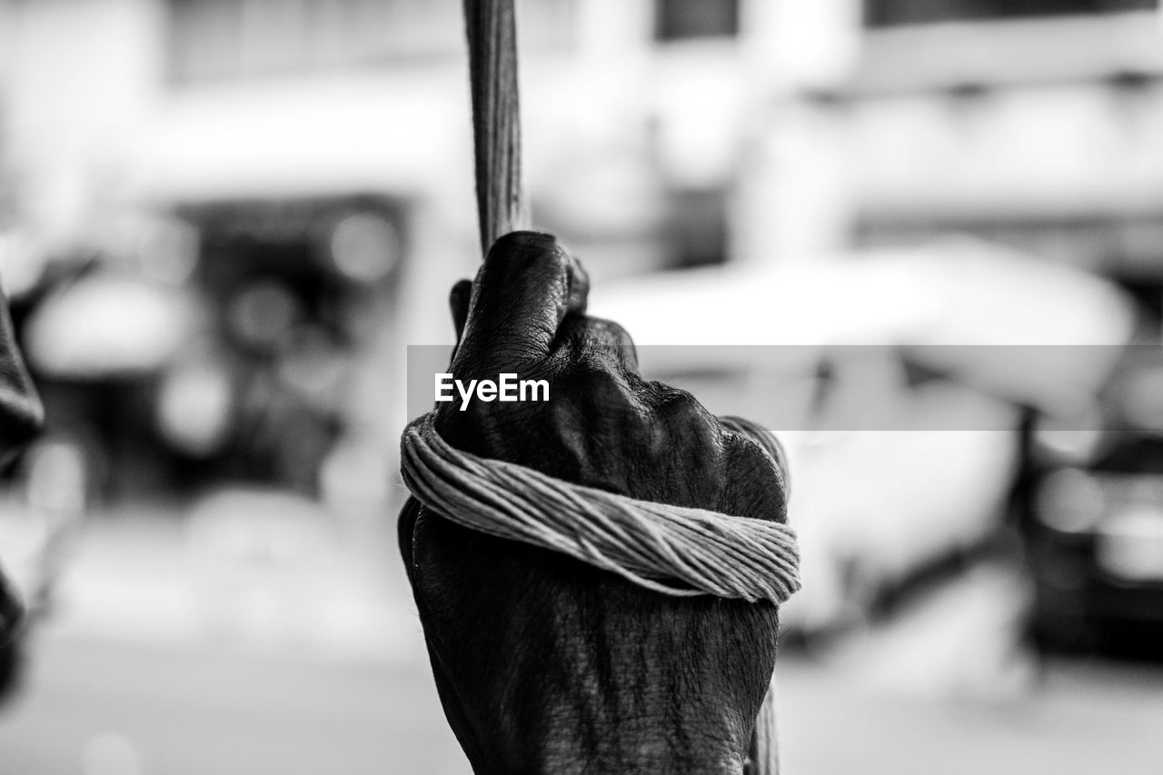 Cropped hand of man holding rope