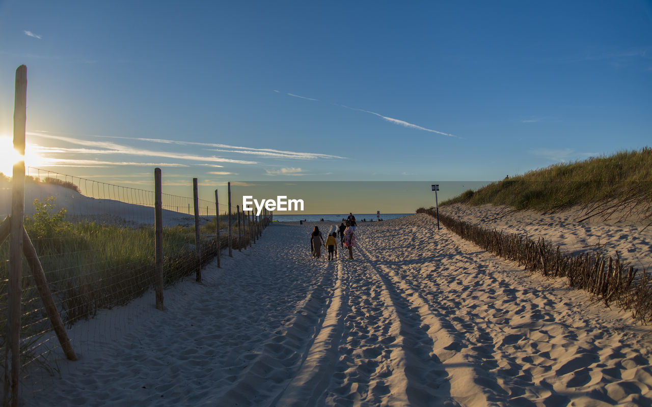 sky, land, nature, landscape, sunlight, morning, environment, sand, horizon, scenics - nature, snow, sea, winter, beauty in nature, beach, walking, sun, natural environment, blue, travel, tranquility, cloud, coast, mountain, outdoors, holiday, vacation, leisure activity, footpath, clear sky, men, transportation, adult, trip, travel destinations, tranquil scene, non-urban scene, water, plant, motion, lifestyles, day, the way forward, sand dune