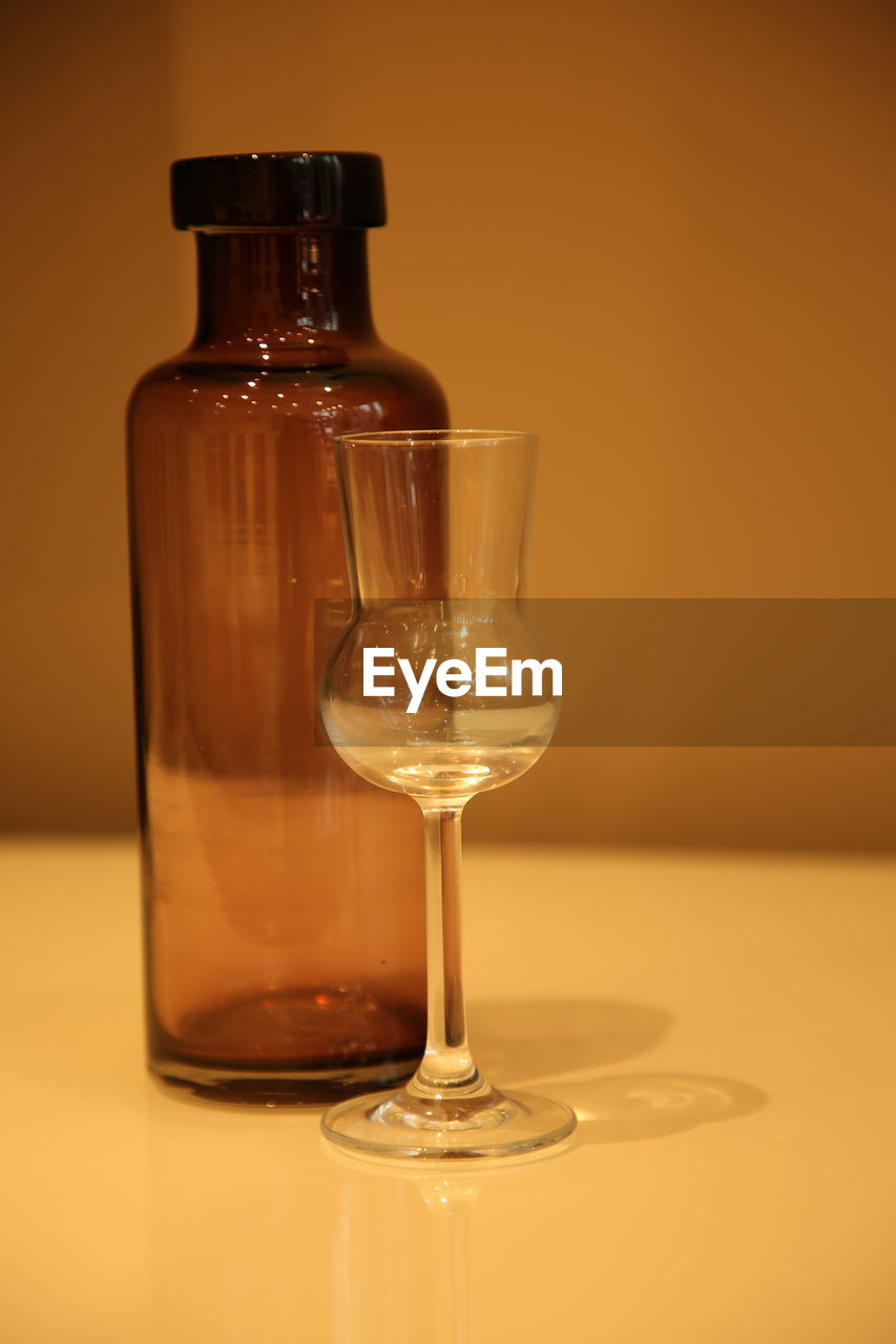 Close-up of empty wineglass and bottle on table