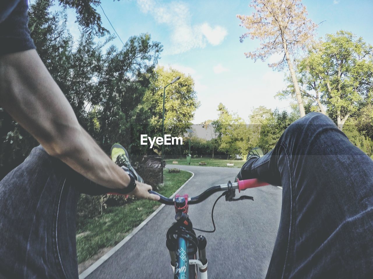 Cropped image of man riding bicycle while feet up on handlebar