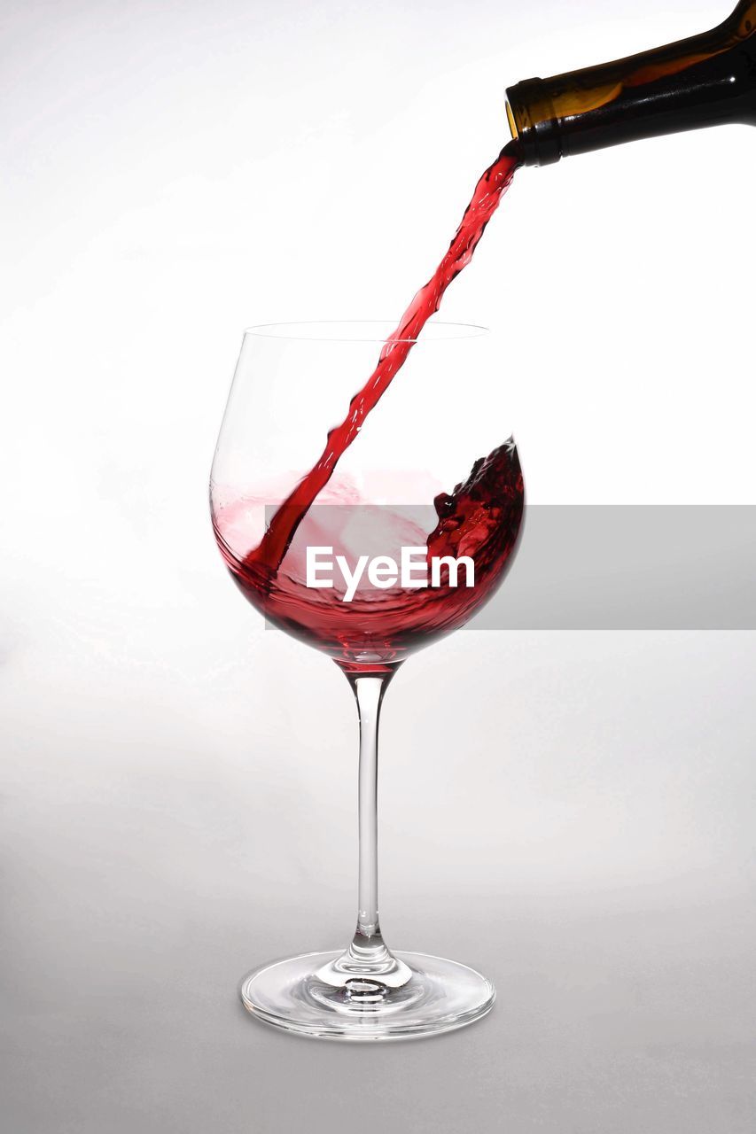 Close-up of red wine in glass against white background