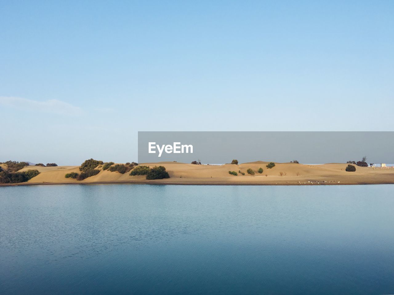 Scenic view of lake against clear blue sky