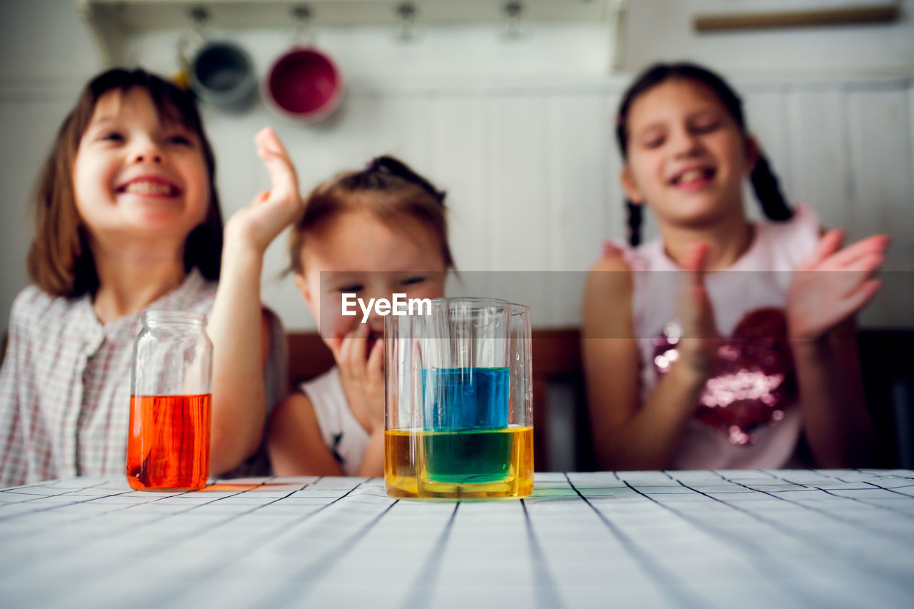 Three cute children play in the kitchen at home with colored liquids. experiments with color at home