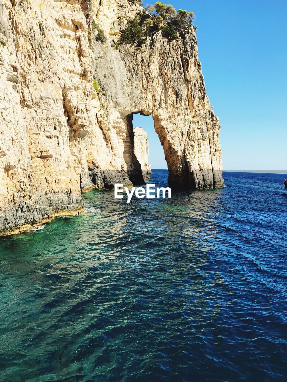 Rock formation by sea against blue sky