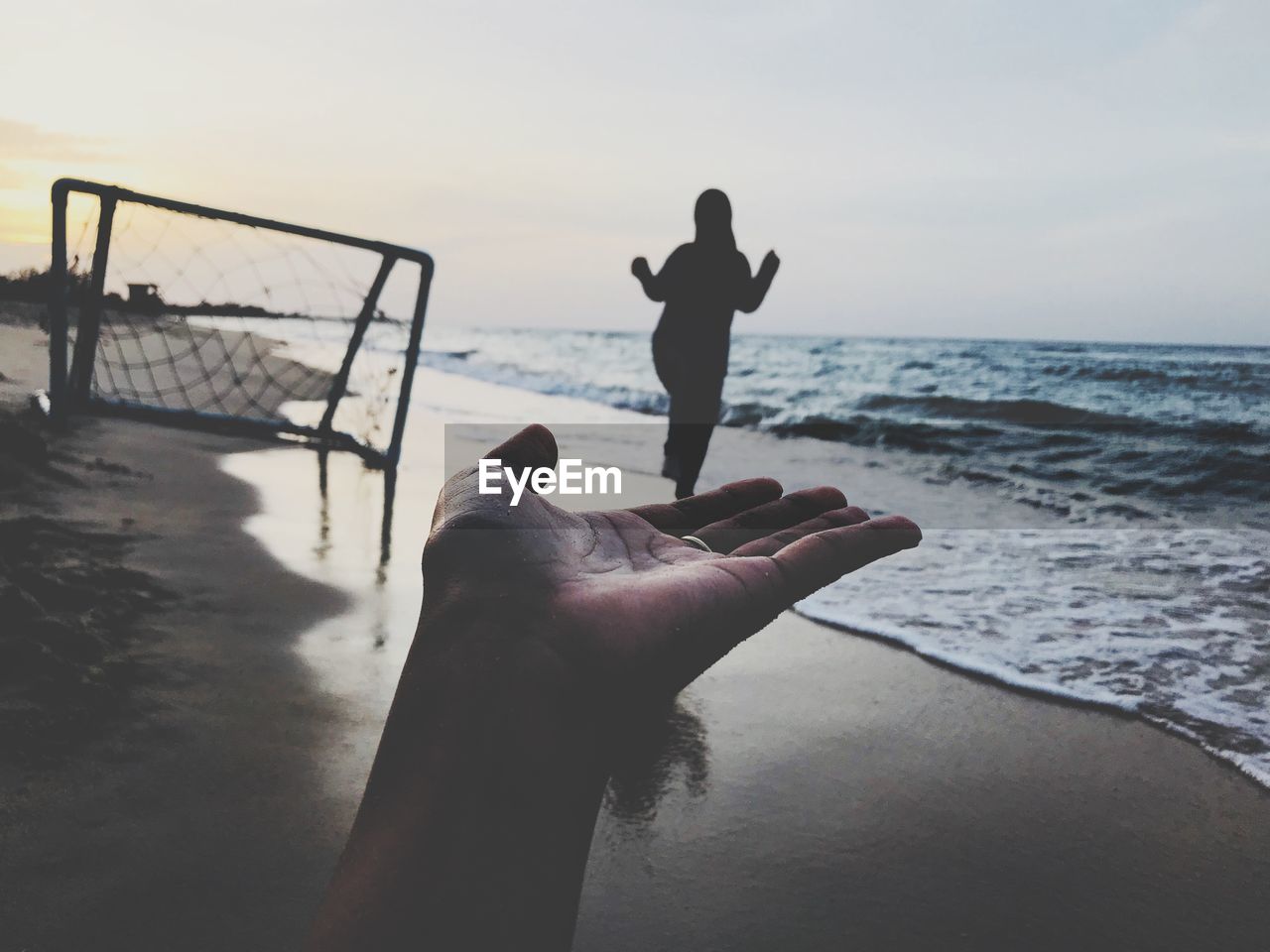 Optical illusion of woman walking on friend hand at beach