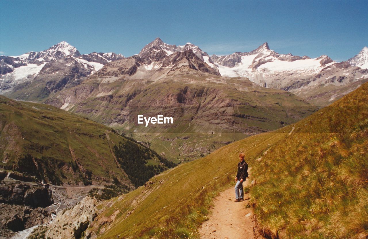 Rear view of man walking on mountain against sky