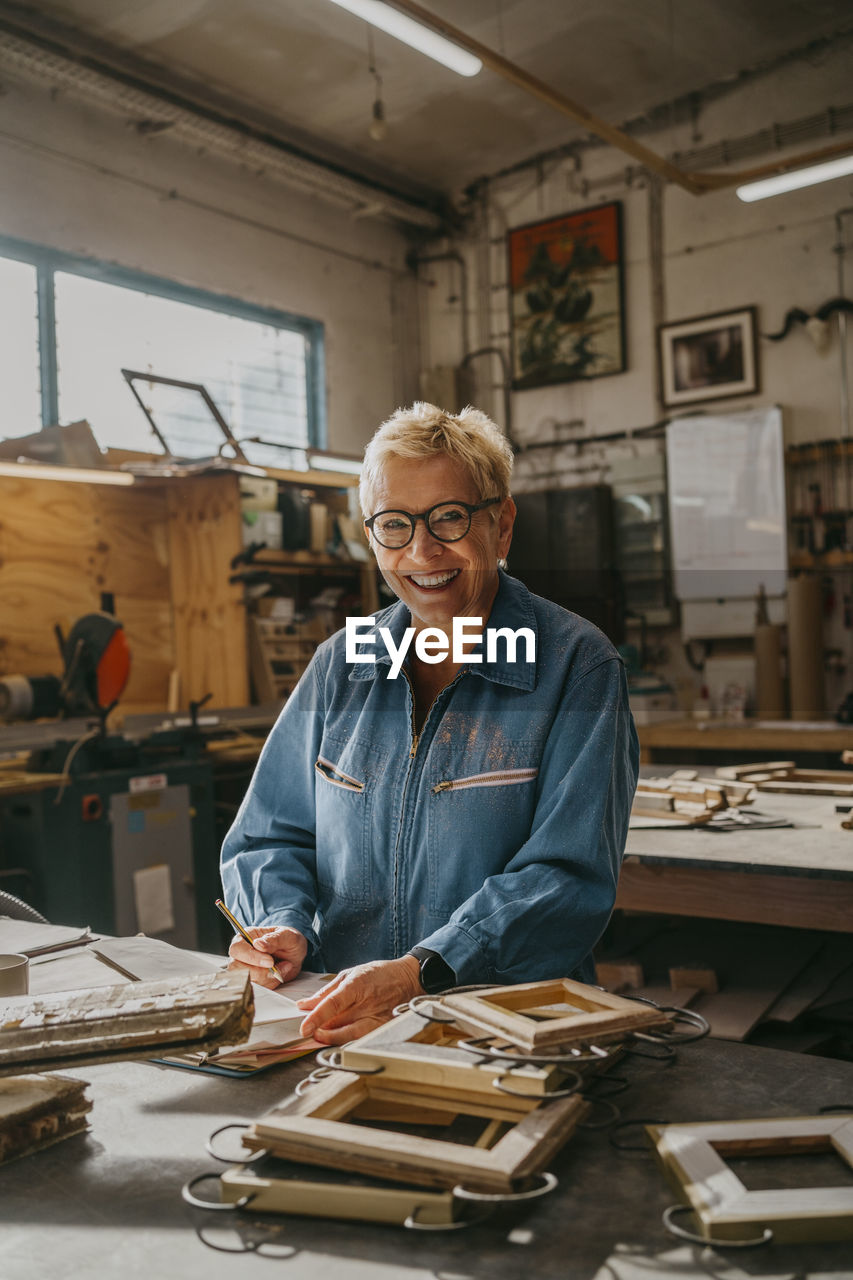 Portrait of happy senior female carpenter at repair shop