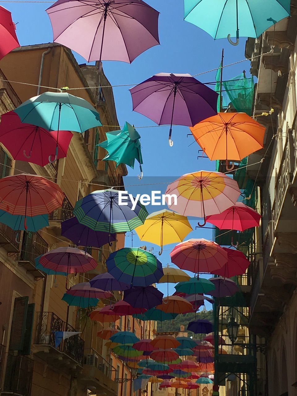 Low angle view of umbrellas hanging amidst buildings against sky