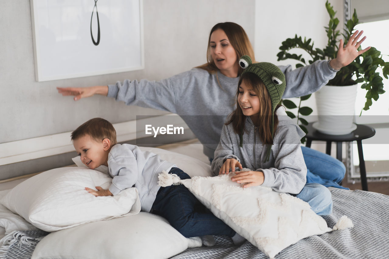 Mother with kids sitting on bed at home