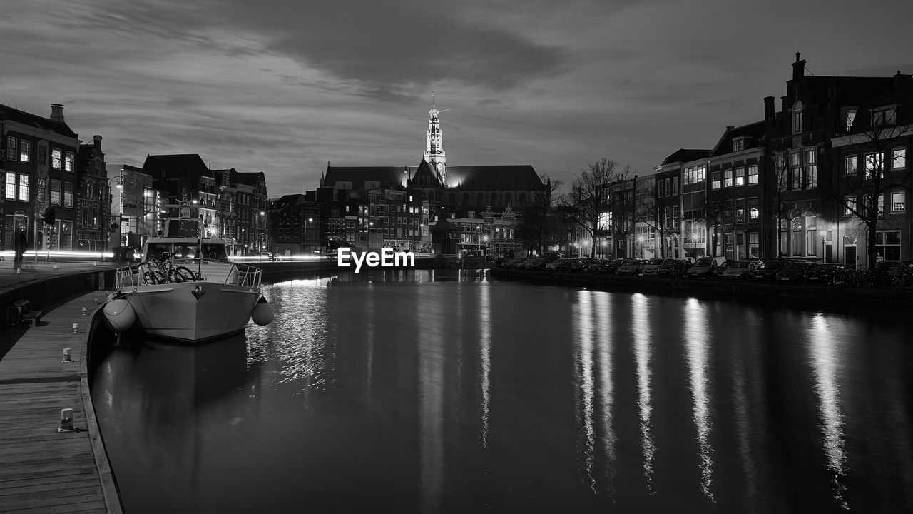 Illuminated grote kerk with reflection in spaarne river against sky at night