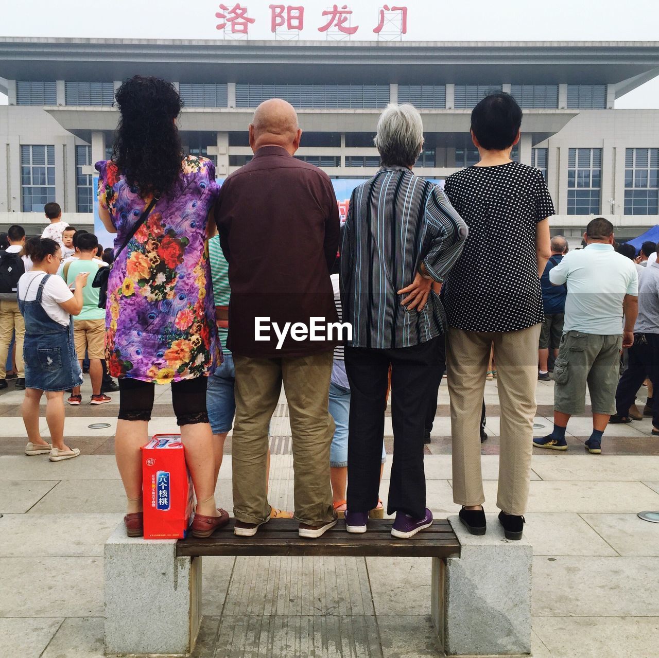 REAR VIEW OF PEOPLE STANDING IN FRONT OF BUILDING