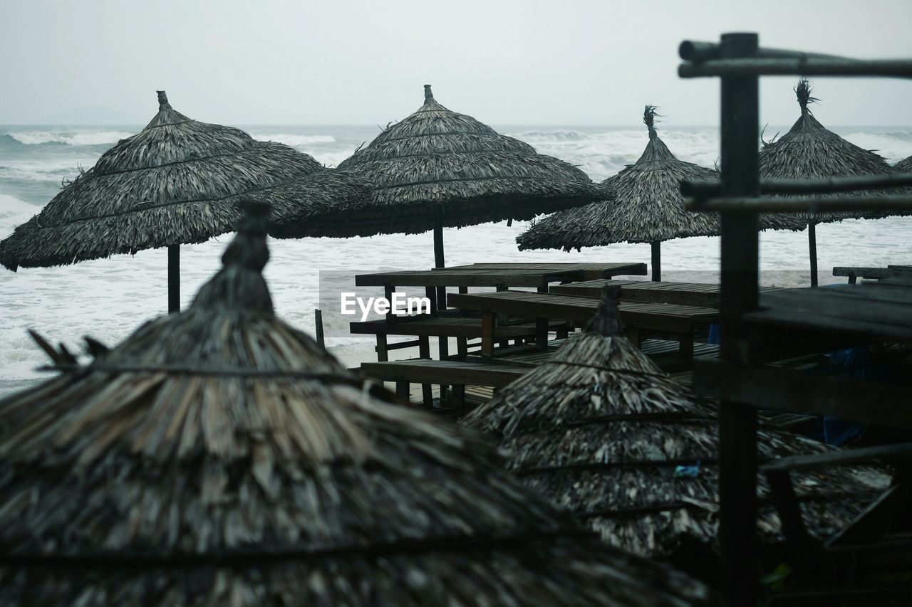 Thatched parasols at beach against sky