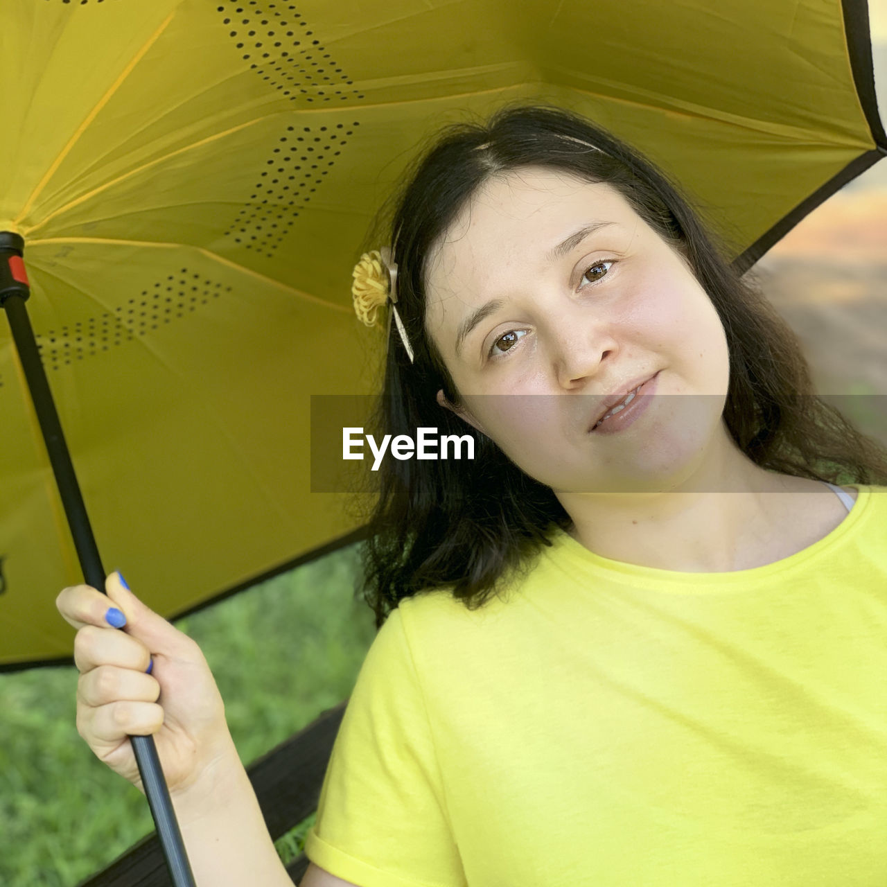 PORTRAIT OF A SMILING YOUNG WOMAN HOLDING YELLOW