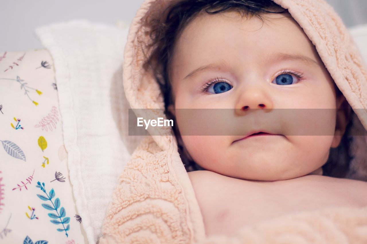 Portrait of cute baby lying on bed at home