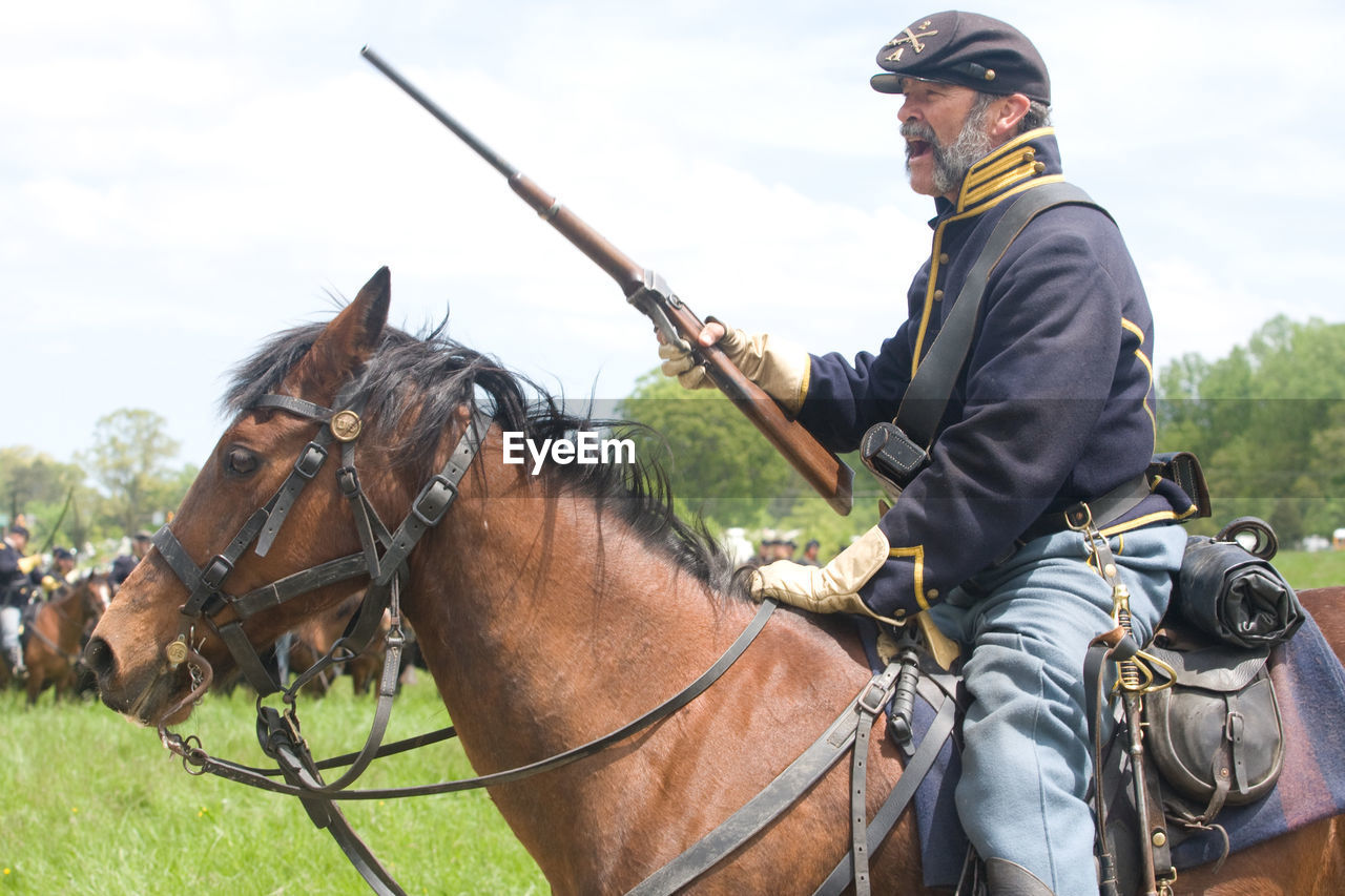 MAN RIDING HORSE ON FIELD