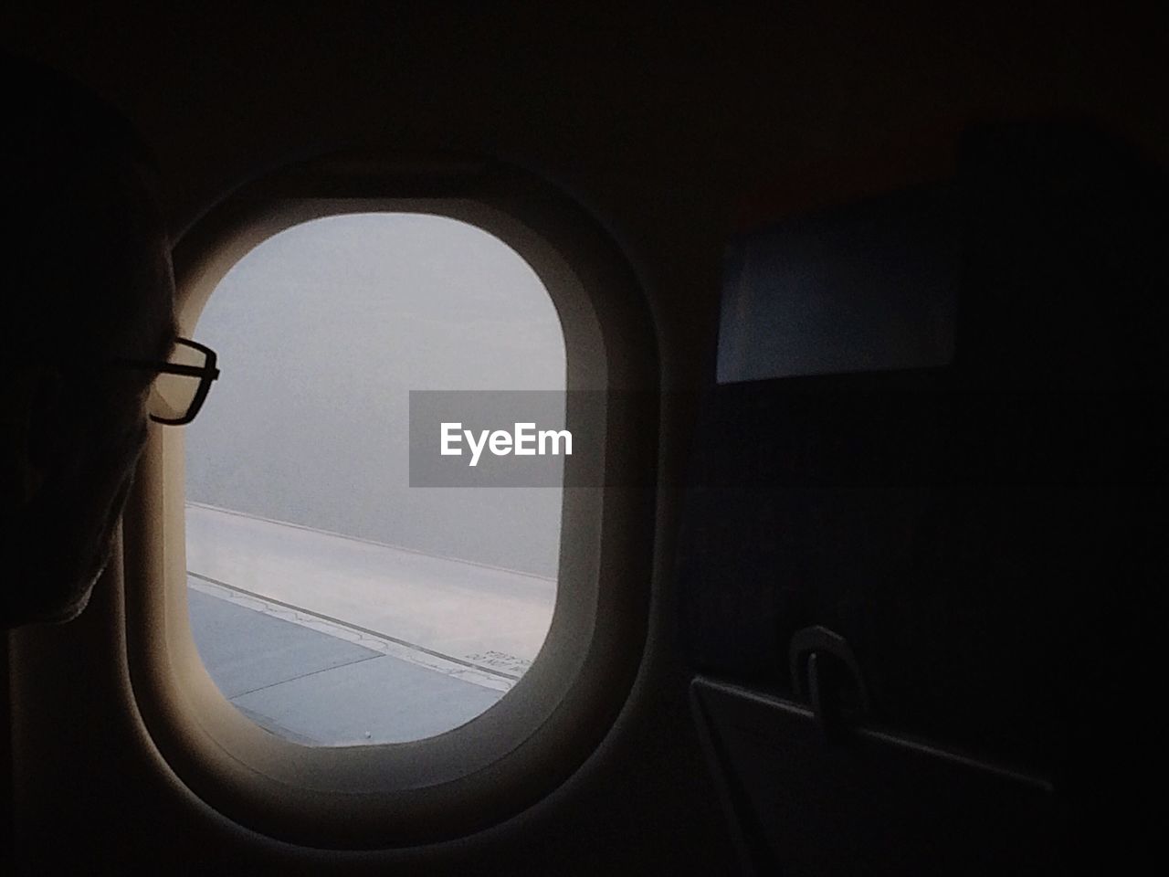 LOW ANGLE VIEW OF AIRPLANE WING SEEN THROUGH WINDOW