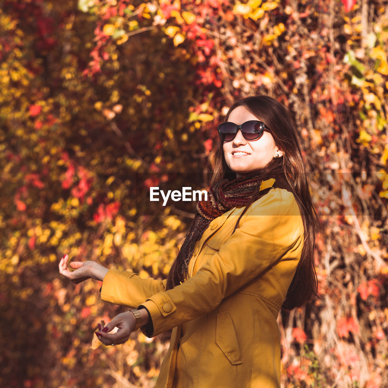 Woman standing by autumn leaves