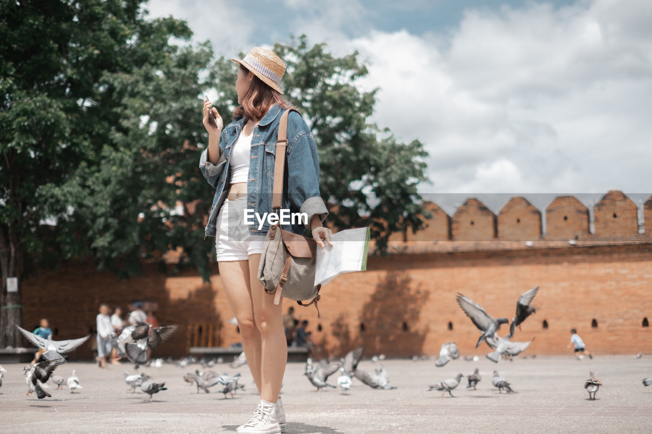 Full length of woman standing by birds outdoors