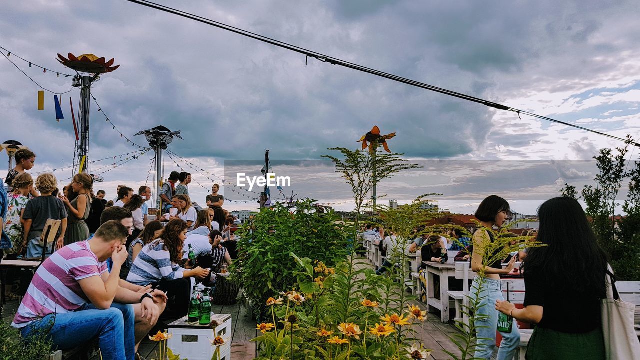 PANORAMIC VIEW OF PEOPLE SITTING ON CHAIR AT BEACH