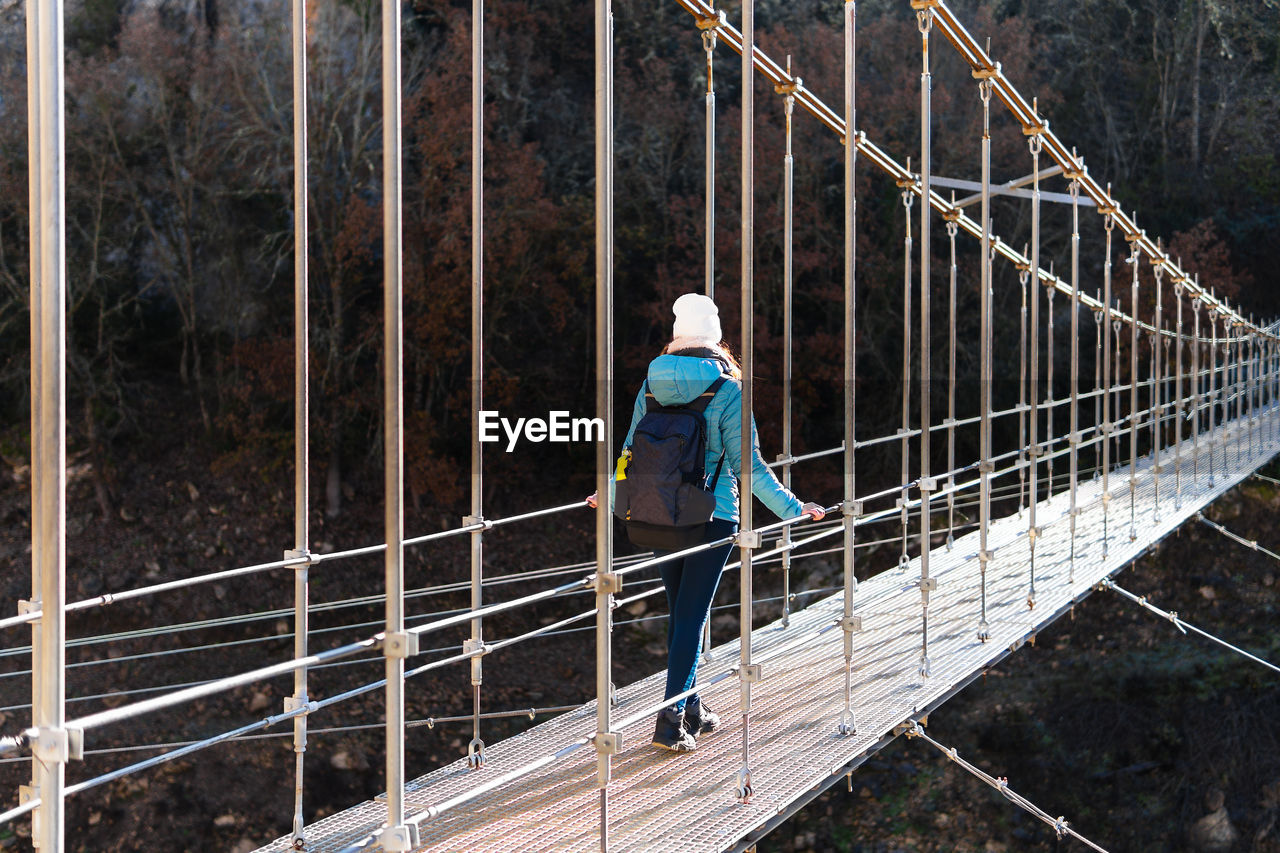 Rear view of woman crossing a high suspension bridge